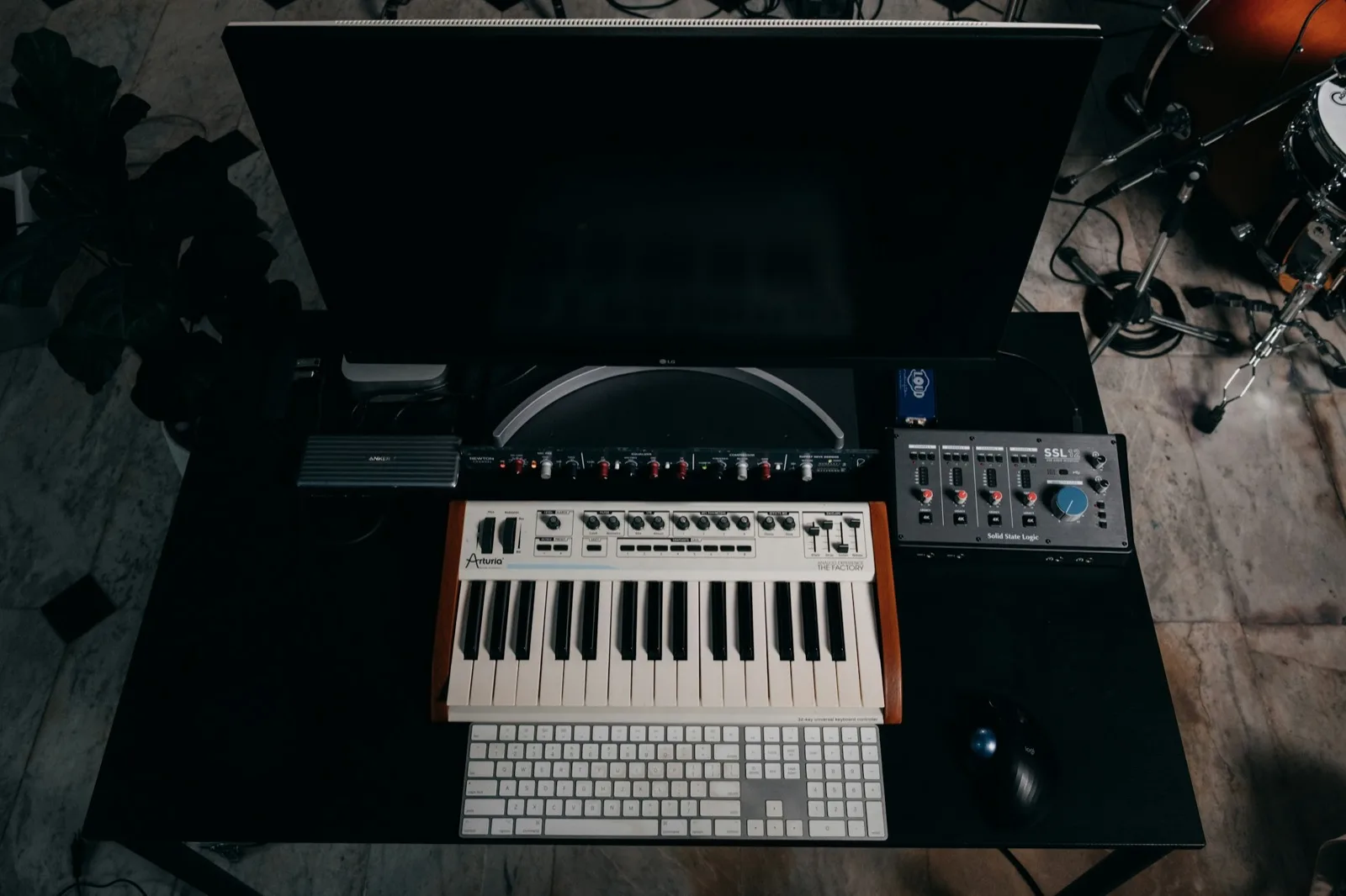 A desk with a keyboard, a synthesizer and audio equipment laid out on it