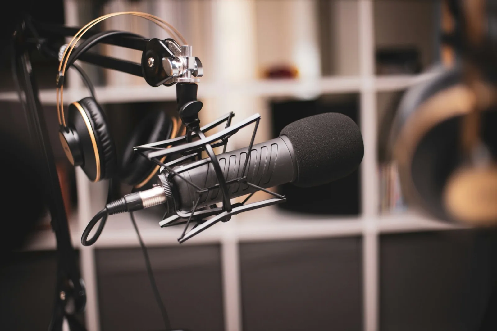 A grey condenser microphone on a stand, lit from one side against a dark studio background
